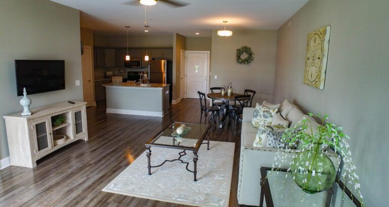 Open-plan living room and kitchen with wood floors, neutral décor, and modern furnishings.